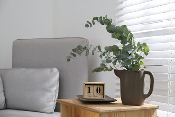 Beautiful eucalyptus branches and block calender on wooden table near window, space for text. Interior element © New Africa