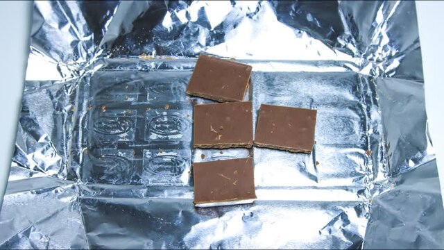 4K Video in stop motion format, as the chocolate wrapper opens and the chocolate slices disappear.