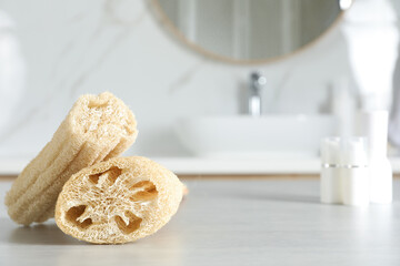 Natural loofah sponges on table in bathroom. Space for text