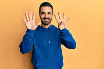 Young hispanic man wearing casual clothes showing and pointing up with fingers number nine while smiling confident and happy.