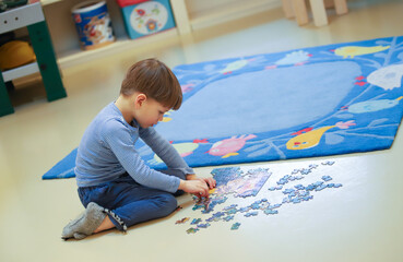 Ein vierjähriger Junge puzzelt auf dem Fußboden