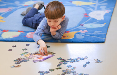 Ein vierjähriger Junge puzzelt auf dem Fußboden