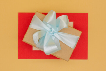 craft gift box with blue satin ribbon on red background
