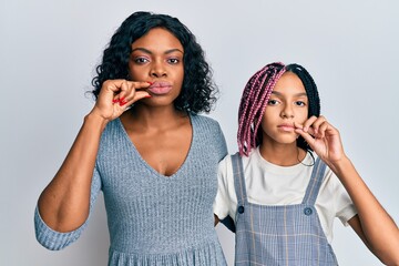 Beautiful african american mother and daughter wearing casual clothes and hugging mouth and lips...