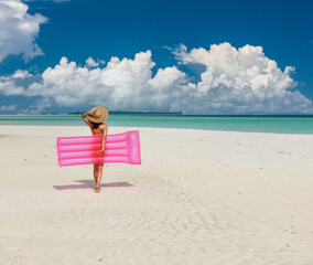 Woman with pink inflatable raft at the beach
