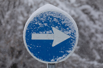 A mandatory one-way traffic sign, covered with snow in the Retiro district, on a snowy day, due to...