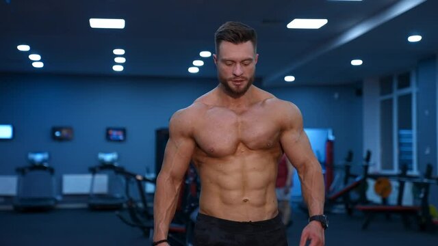 Muscle athlete strongman walks in a gym after heavy training. Perfect torso with strong abs. Handsome power male with naked torso.
