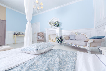 bright, clean stylish interior bedroom and living room with a large panoramic window. beautiful rich antique furniture. four-poster bed, a mirror and a sofa.