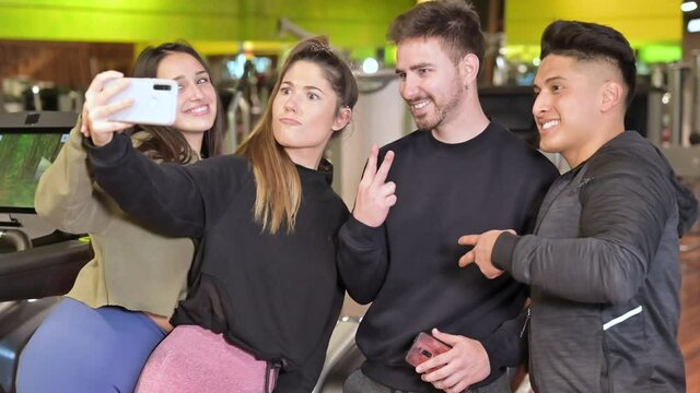 Group of sporty people in sportswear taking selfie photo with mobile phone at gym. High quality 4k footage