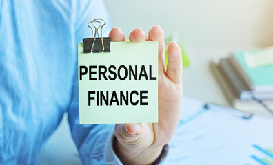 PERSONAL FINANCE written on a voucher shown by a female businessman. Soft focus.
