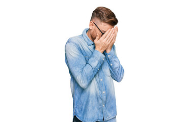 Young redhead man wearing casual denim shirt with sad expression covering face with hands while...
