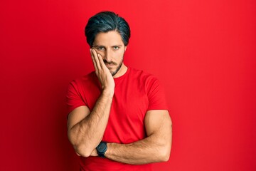 Young hispanic man wearing casual red t shirt thinking looking tired and bored with depression problems with crossed arms.