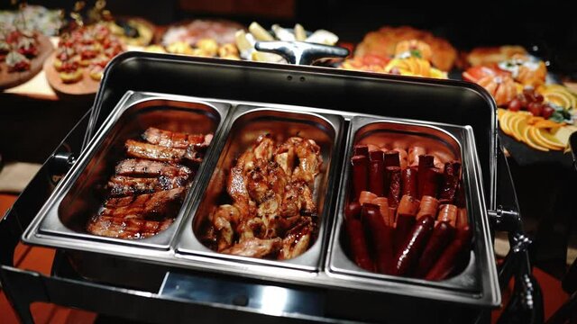 Buffet heated trays with sausages, in hotel luxury restaurant. All inclusive. Buffet food. Hotel serves buffet for breakfast. People with plates choose their dishes. Dining at the hotel of Egypt
