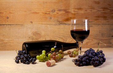 A glass of red wine with grapes and bottle