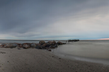 Fototapeta na wymiar Remains of an old pier, old breakwater posts on beach, Lapmezciems, Latvia