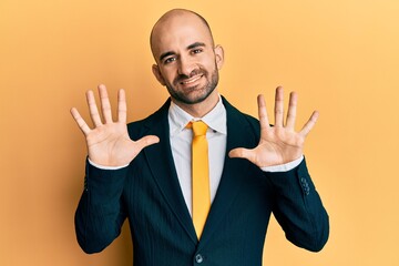 Young hispanic man wearing business suit and tie showing and pointing up with fingers number ten while smiling confident and happy.