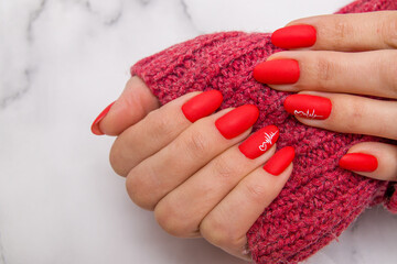 Red matte manicure with a heart pattern and a cardiogram on a female hands for valentine's day