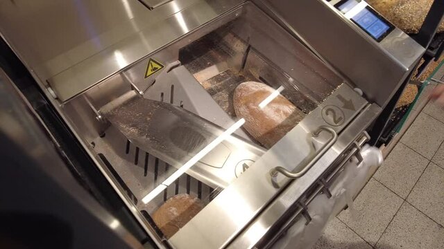 Ein Brot wird in der Brotschneidemaschine geschnitten