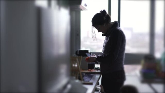 Candid mother cooking and taking care of baby at the same time, mom multi-tasking