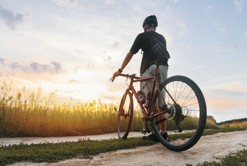 Cyclist in the field enjoying the sunset after sport training.