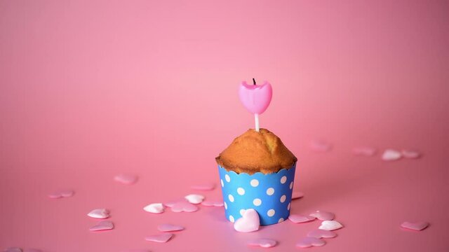 4k One cupcake or muffin with pink heart shape candle, flame blow out on a pink background, Celebration Valentine's day, birthday. love is finished