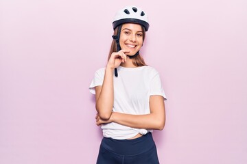 Young beautiful girl wearing bike helmet smiling looking confident at the camera with crossed arms and hand on chin. thinking positive.