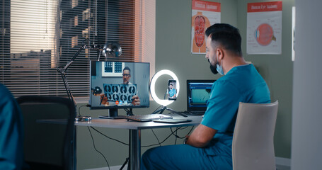 Male doctor discussing X ray scan with online coworker