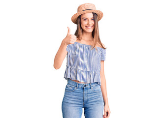 Obraz na płótnie Canvas Young beautiful girl wearing hat and t shirt doing happy thumbs up gesture with hand. approving expression looking at the camera showing success.
