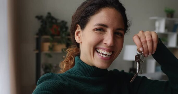 Close up webcam view happy 35s single lady record video for memory vlog channel show bunch of keys to camera from bought own, rented apartment at moving day. New real estate ownership, tenancy concept