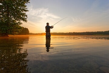 angler catching the fish during summer sunrise