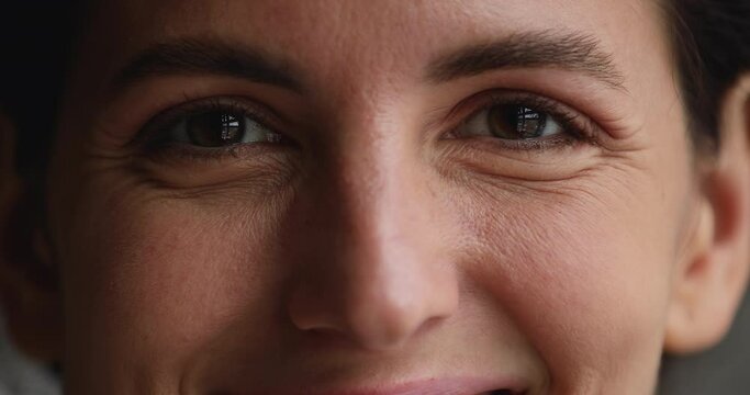 Extreme close up view part of smiling beautiful 30s woman face, eyebrows, nose, mimic wrinkles under happy eyes looking at camera. skincare cosmetology, anti aging treatment, eyesight surgery concept