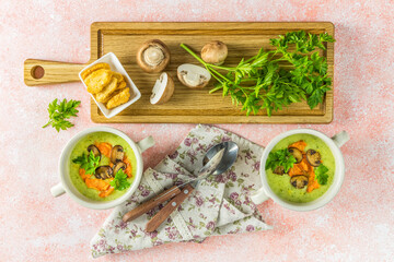 Healthy delicious potato cauliflower soup puree with carrot chips and croutons on a pink background, top view