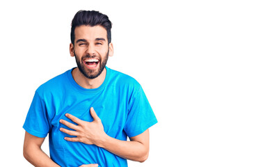 Fototapeta premium Young handsome man with beard wearing casual t-shirt smiling and laughing hard out loud because funny crazy joke with hands on body.