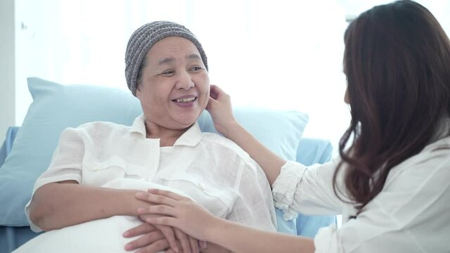 senior cancer patient have a hug with her daughter, a young woman visits her mother at the hospital, older people healthcare support concept, smile and happy with the family