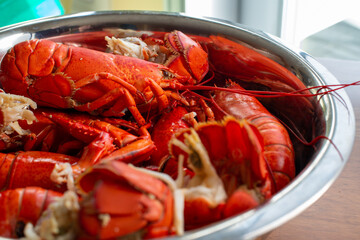 A large bowl of cooked lobster sits on a table in a restaurant near a brightly lit window. The...