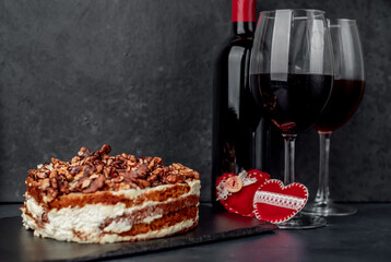 delicious cake with nuts and chocolate, wine and glasses on a stone background