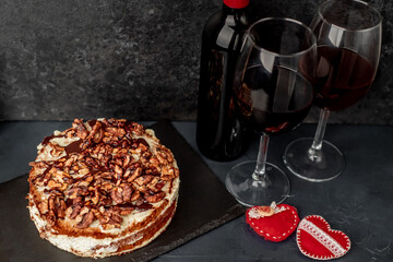 delicious cake with nuts and chocolate, wine and glasses on a stone background