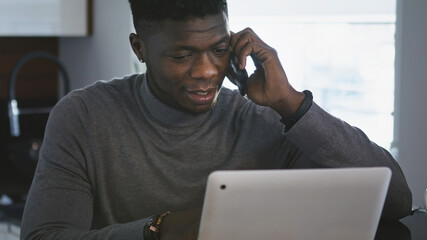 African american black businessman working on the laptop and having phone call in his appartment. High quality photo