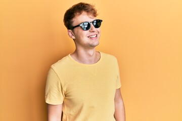 Young caucasian man wearing stylish sunglasses looking to side, relax profile pose with natural face and confident smile.