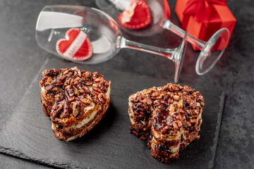 Two cakes with heart shaped nuts for valentine's day and glasses of wine on a stone background