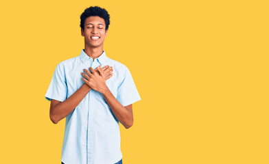 Young african american man wearing casual clothes smiling with hands on chest with closed eyes and grateful gesture on face. health concept.