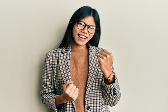 Young chinese woman wearing business style and glasses celebrating surprised and amazed for success with arms raised and eyes closed. winner concept.