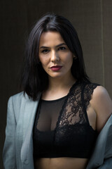Fototapeta premium Portrait of a young sexy brunette girl in a lace top in dramatic tones. Vintage photo.
