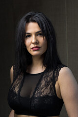 Fototapeta premium Portrait of a young sexy brunette girl in a lace top in dramatic tones. Vintage photo.