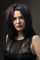 Fototapeta premium Portrait of a young sexy brunette girl in a lace top in dramatic tones. Vintage photo.