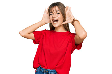 Teenager caucasian girl wearing casual red t shirt smiling cheerful playing peek a boo with hands showing face. surprised and exited