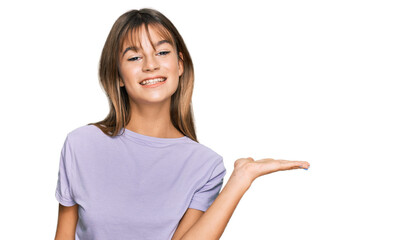 Teenager caucasian girl wearing casual clothes smiling cheerful presenting and pointing with palm of hand looking at the camera.