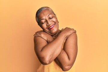 Senior african american woman wearing casual style with sleeveless shirt hugging oneself happy and positive, smiling confident. self love and self care - Powered by Adobe