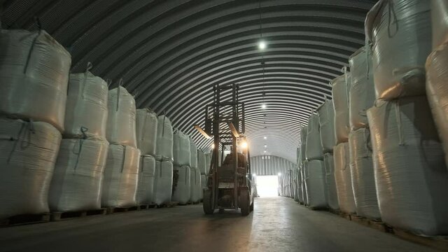 Warehousing. Forklift driver stacking big bag of raw material in warehouse. 
Many bags of raw materials in the warehouse