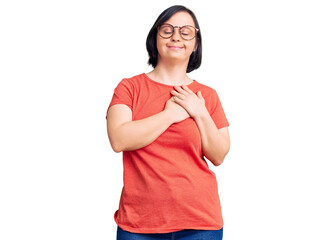 Brunette woman with down syndrome wearing casual clothes and glasses smiling with hands on chest...